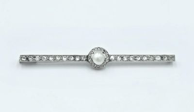 un gros plan d'une bague sertie d'un diamant et d'une perle sur fond blanc