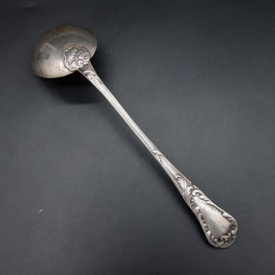 an antique silver spoon on a black surface with a black background