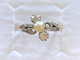 une bague sertie d'une perle, posée sur un tissu blanc