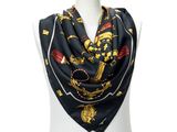 a woman wearing a black scarf with gold and red symbols on it