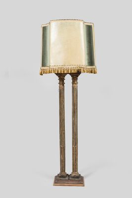 a tall brass table lamp with a gold shade on top of it