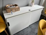 a white cabinet and yellow chairs in a room