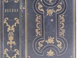 an old blue book with gold designs on it sitting on top of a white surface