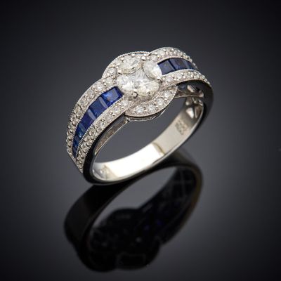 un gros plan d'une bague sertie d'un diamant et d'un saphir sur une surface noire
