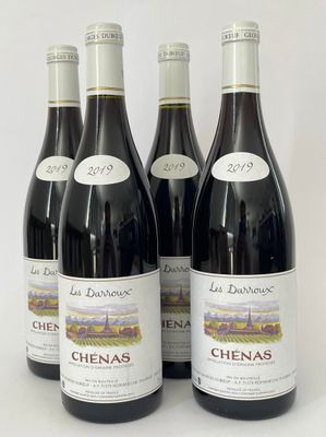 quatre bouteilles de vin rouge sont alignées sur une surface blanche