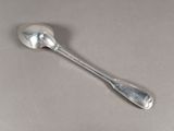cuillère en argent à long manche posée sur une surface grise