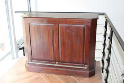 une armoire en bois posée sur un parquet, près d'une fenêtre