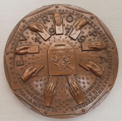une médaille de bronze sur laquelle sont représentées des mains, posée sur un fond blanc