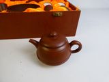 a brown teapot sitting next to a box of oranges