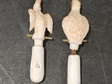 pair of white ceramic figurines of two birds on a wooden stand