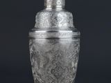 a silver plated cocktail shaker on a black background