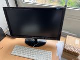 a computer monitor and keyboard on a desk in front of a window