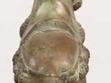 bronze statue of a horse on a wooden table with a white wall in the background