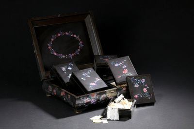 a small doll sitting in a suitcase next to a pile of cards