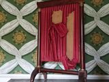 une chaise rouge recouverte d'un rideau rouge, placée devant un mur recouvert de papier peint vert