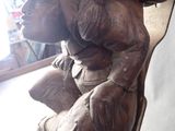 a wooden sculpture of a man sitting on a bench
