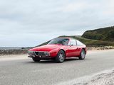a red car driving down the road by the ocean
