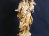 statue of a woman holding a child on a pedestal against a black background
