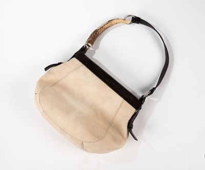 un gros plan d'un sac à main posé sur une surface blanche, muni d'une anse noire