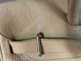 the inside of a tan purse with a metal handle