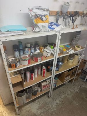 a shelf full of paint and other items in a room