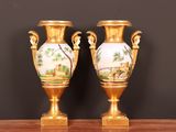 deux vases en or posés sur une table en bois, sur fond noir