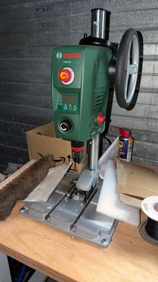 a drill on a table with a box and a cup of coffee