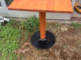 une petite table en bois posée à même le sol, avec un piètement noir