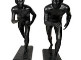Deux statues représentant un homme et une femme se dressent sur un socle noir.