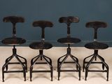 four wooden stools sitting on top of a white floor next to a blue wall