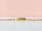 un bracelet en or avec une barre suspendue à une chaîne, sur fond rose