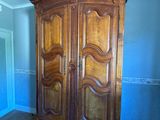 a wooden armoire in the corner of a room