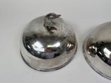 two silver plates with a bird on them on a table