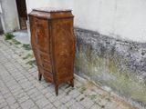 une vieille armoire en bois posée contre un mur, sur le trottoir