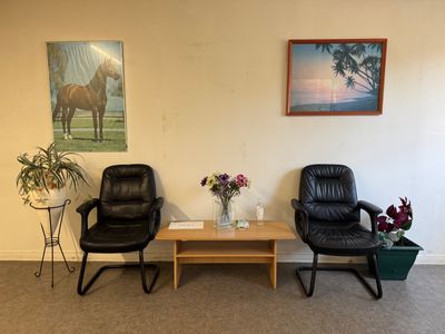 deux chaises et une table dans une pièce où est accroché un tableau au mur