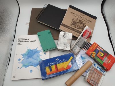 une table blanche sur laquelle sont posés un cahier, des stylos, des crayons et d'autres fournitures scolaires