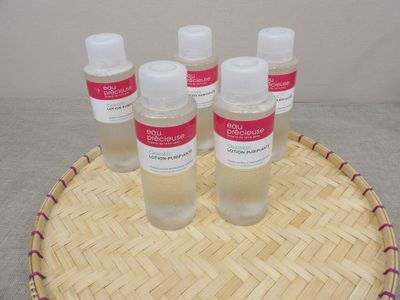 quatre flacons de gel hydroalcoolique posés sur un plateau en bambou