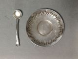 une assiette en argent avec une cuillère et un repose-cuillère posés sur une table