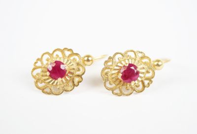 a pair of gold earrings with a ruby stone