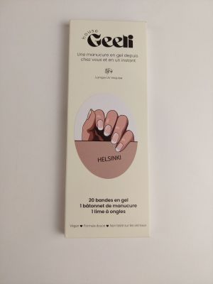 Quelqu'un tient une boîte de vernis à ongles sur une table blanche.
