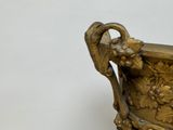 a gold vase with a bird on it on a table