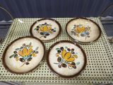 four plates with yellow flowers on them sitting on a table