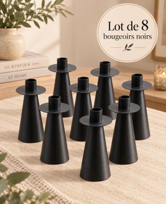 plusieurs bougeoirs noirs posés sur une table, avec une plante en arrière-plan