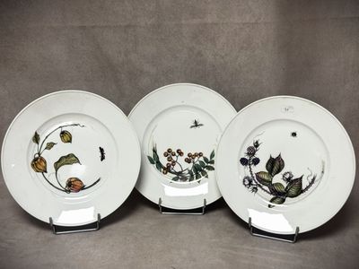 trois assiettes ornées de fleurs et de feuilles, posées sur une table