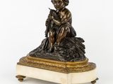 une figurine antique en bronze représentant un garçon assis sur un rocher
