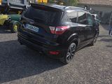 a black car parked in a parking lot with other cars