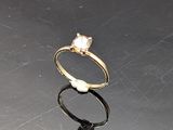 a gold ring with a white stone on a table
