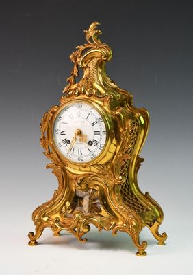 une horloge en or posée sur une table blanche