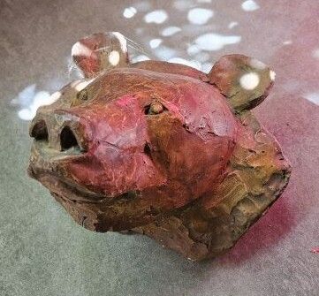 une tête de cochon en argile posée sur une table