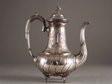a silver tea pot with a handle on a table